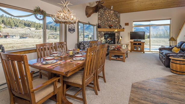A dining area with a wooden table set for four, surrounded by chairs.
