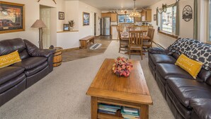 A living room with a sofa, coffee table, and a dining area with chairs and a table.