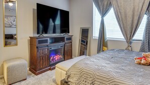 Ein Schlafzimmer mit Fernseher, Kamin, Bett und einem Teddybären.
