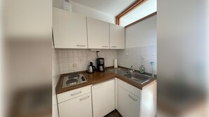 A kitchen with white cabinets, a coffee maker, a kettle, and a sink.