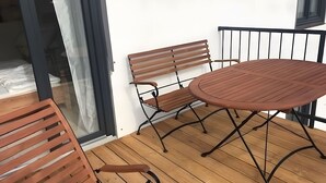 A balcony with a wooden table and two benches.