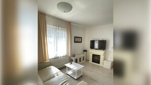 A living room with a sofa, a coffee table, a television, a fireplace, and a radiator.