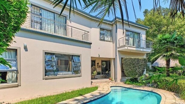 Una casa moderna de dos pisos con piscina, balcón y un jardín bien cuidado.
