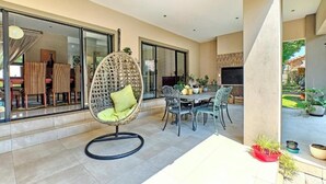 Un patio moderno al aire libre con una mesa de comedor, sillas y una hamaca colgante.