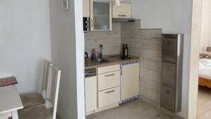 A compact kitchen with a refrigerator, a sink, and cabinets.