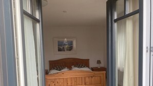 A bedroom with a wooden bed, a nightstand, a lamp, and a framed picture on the wall.