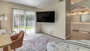 A modern living room with a flat-screen TV, a sofa, a coffee table, and a patterned rug.