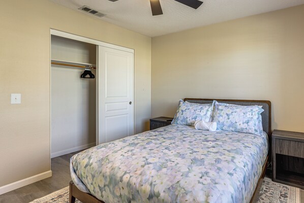 A bedroom with a bed, a closet, a nightstand, and a patterned rug. - Spring Valley Lake Home w/ Desk & Fenced Yard (Victorville)