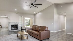 A spacious living room with a leather sofa, a coffee table, and a fireplace.