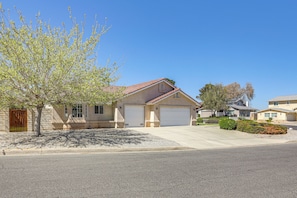 A residential house with a garage, a driveway, and a tree in front.