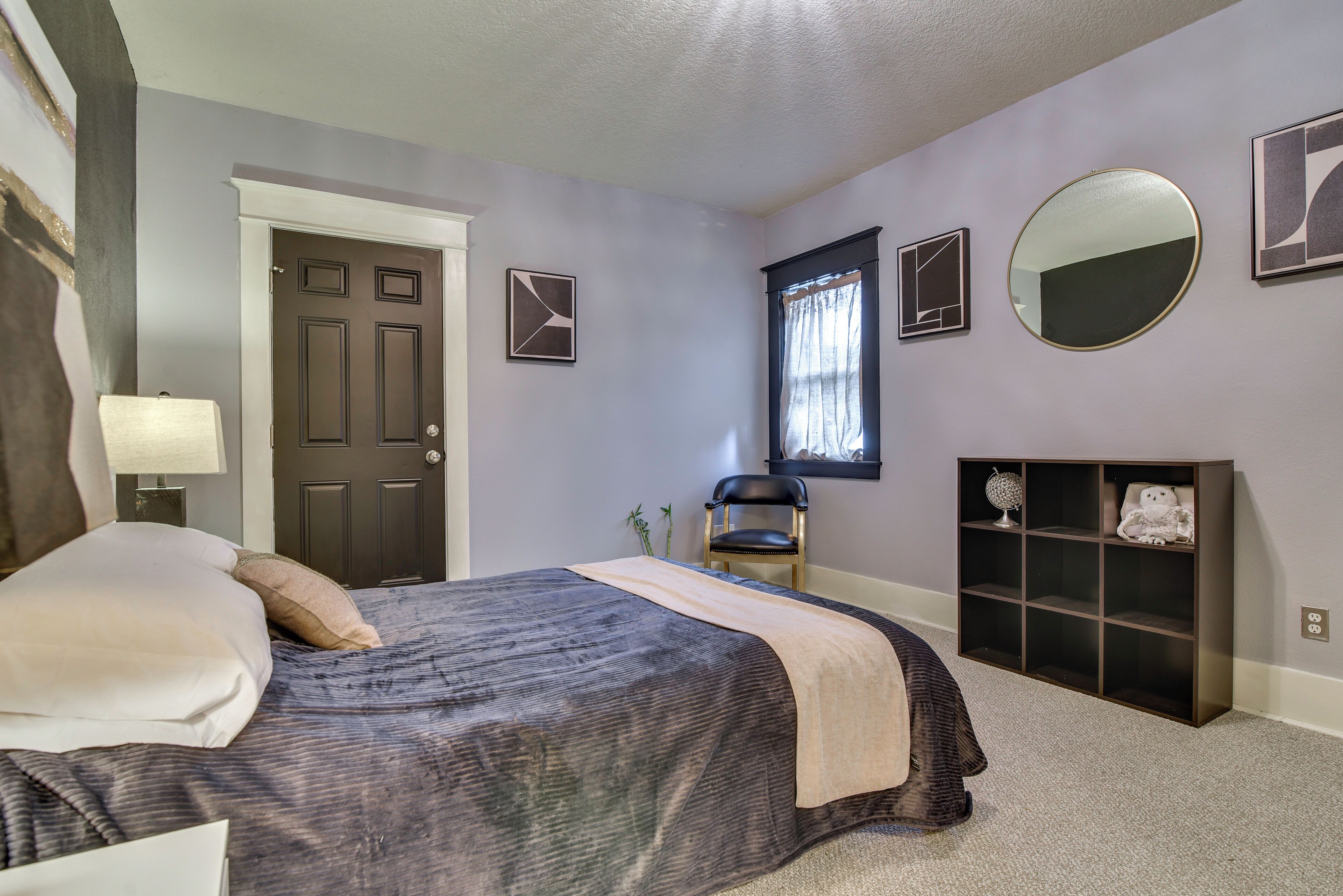 Ein Schlafzimmer mit einem Bett, einem Sessel, einem Bücherregal und einer Tür.