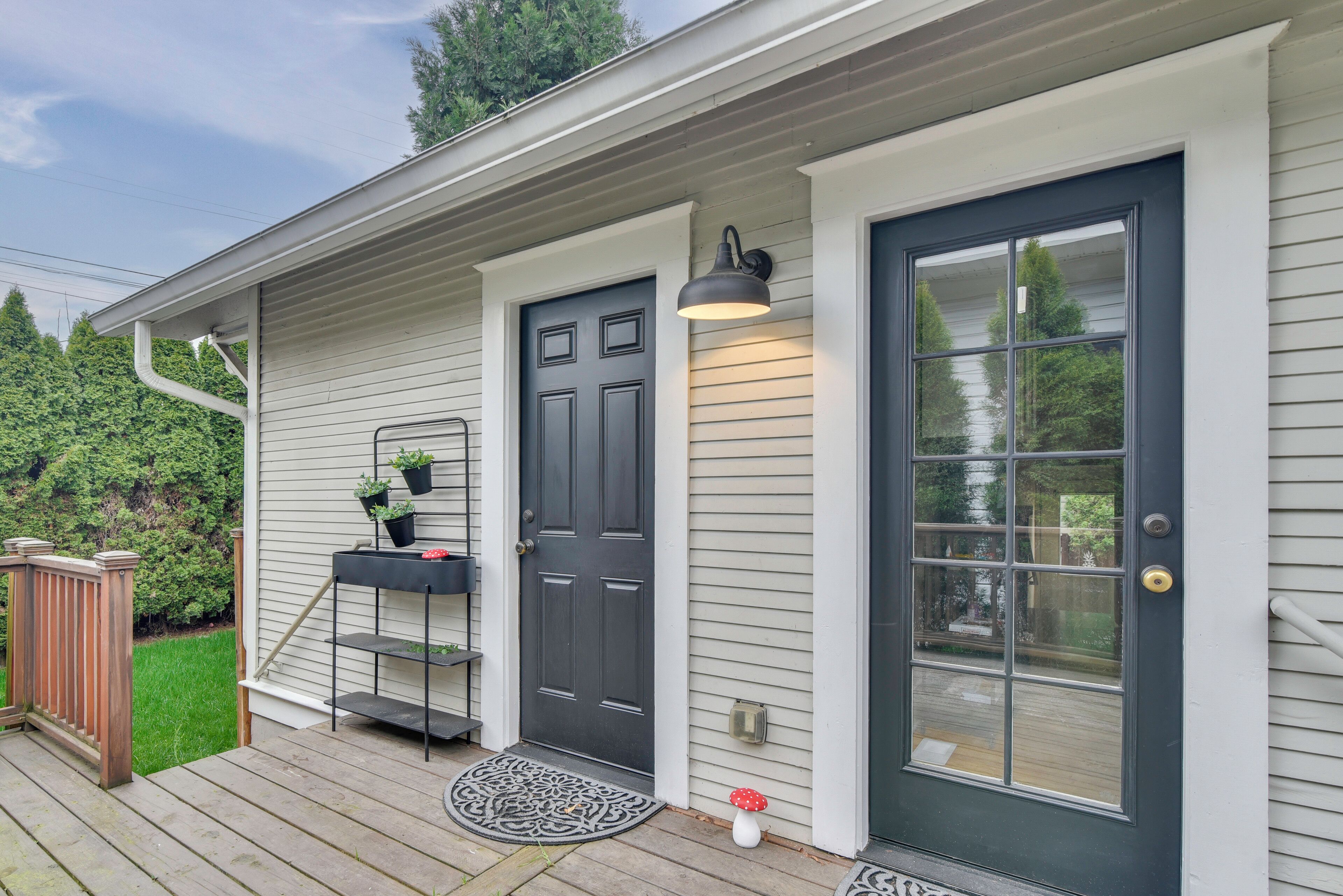 A house with a dark front door, a small porch with a bench, and a wall-mounted light fixture.