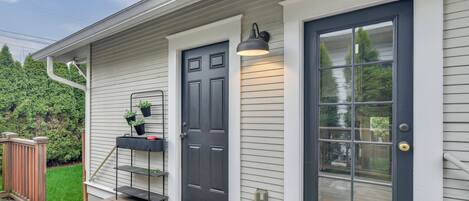 A house with a dark front door, a small porch with a bench, and a wall-mounted light fixture.