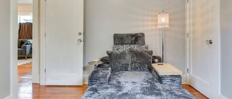 A bedroom with a bed, bedside table, lamp, and a door leading to another room.