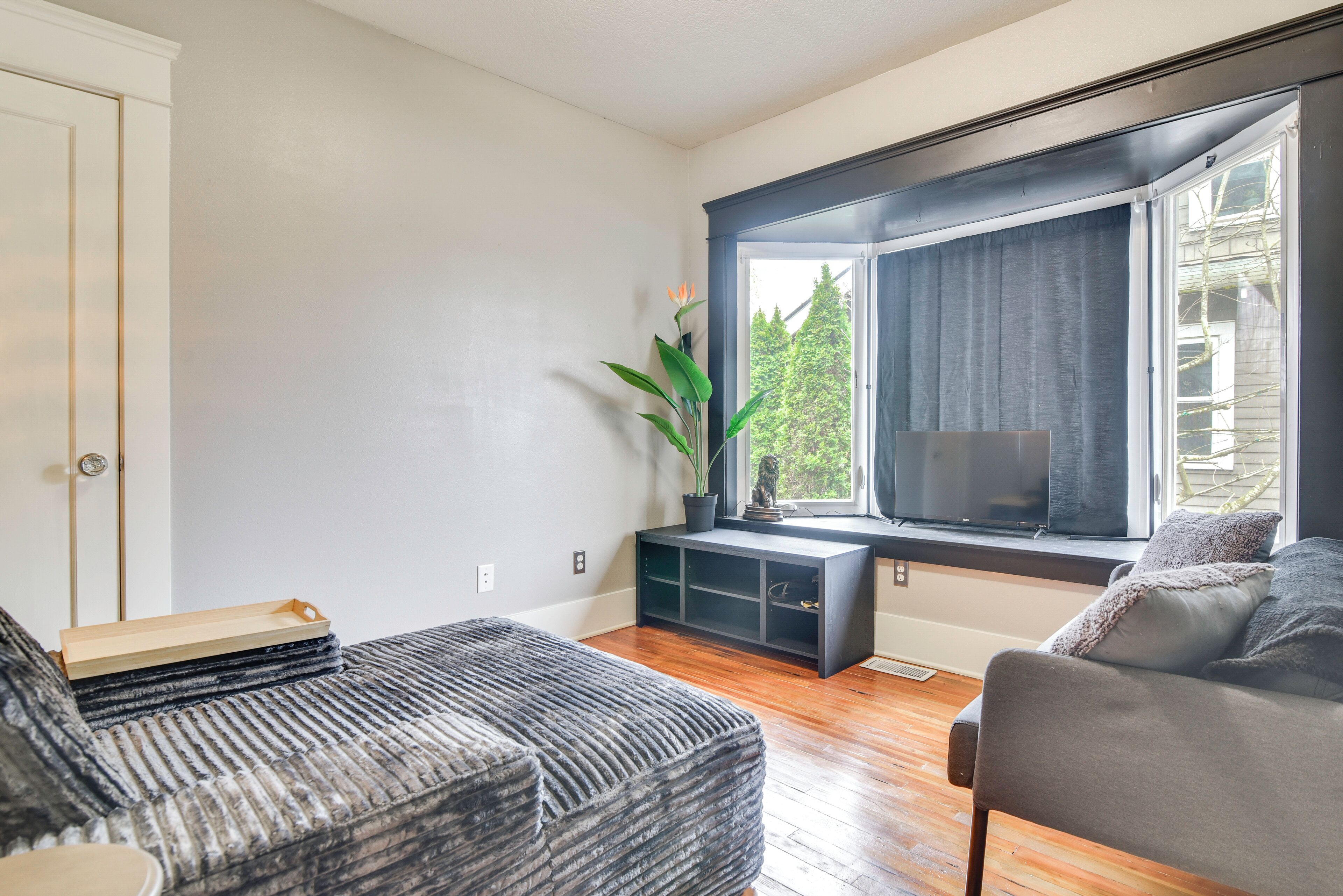 A modern living room with a sofa, a coffee table, a TV, and a window with curtains.