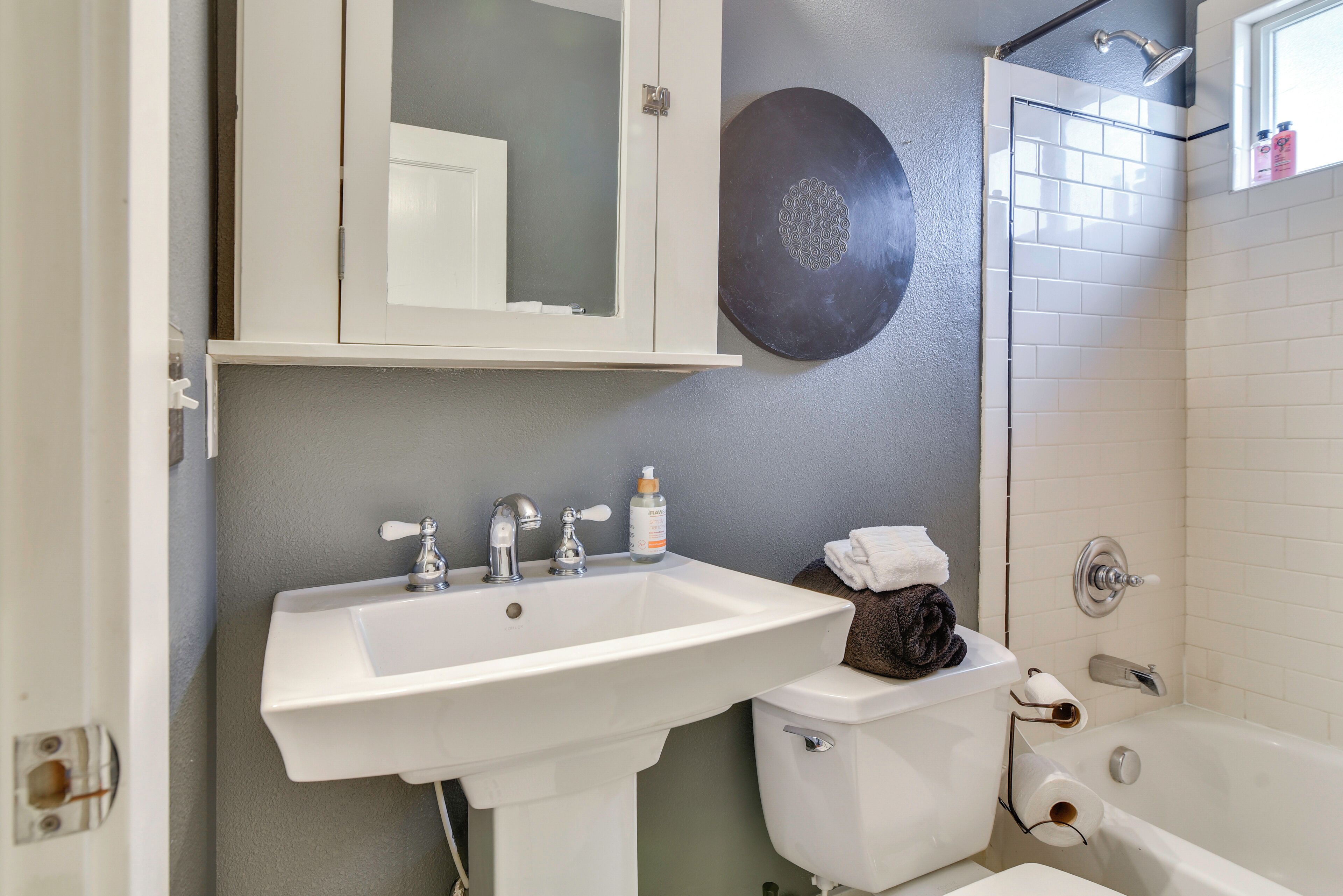 Un baño con lavamanos, inodoro y bañera blancos.