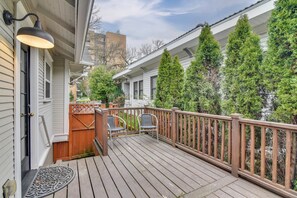 A wooden deck with a railing, two chairs, and a door with a light fixture. - Main Street Retreat! Urban Cottage in Vancouver (Vancouver)