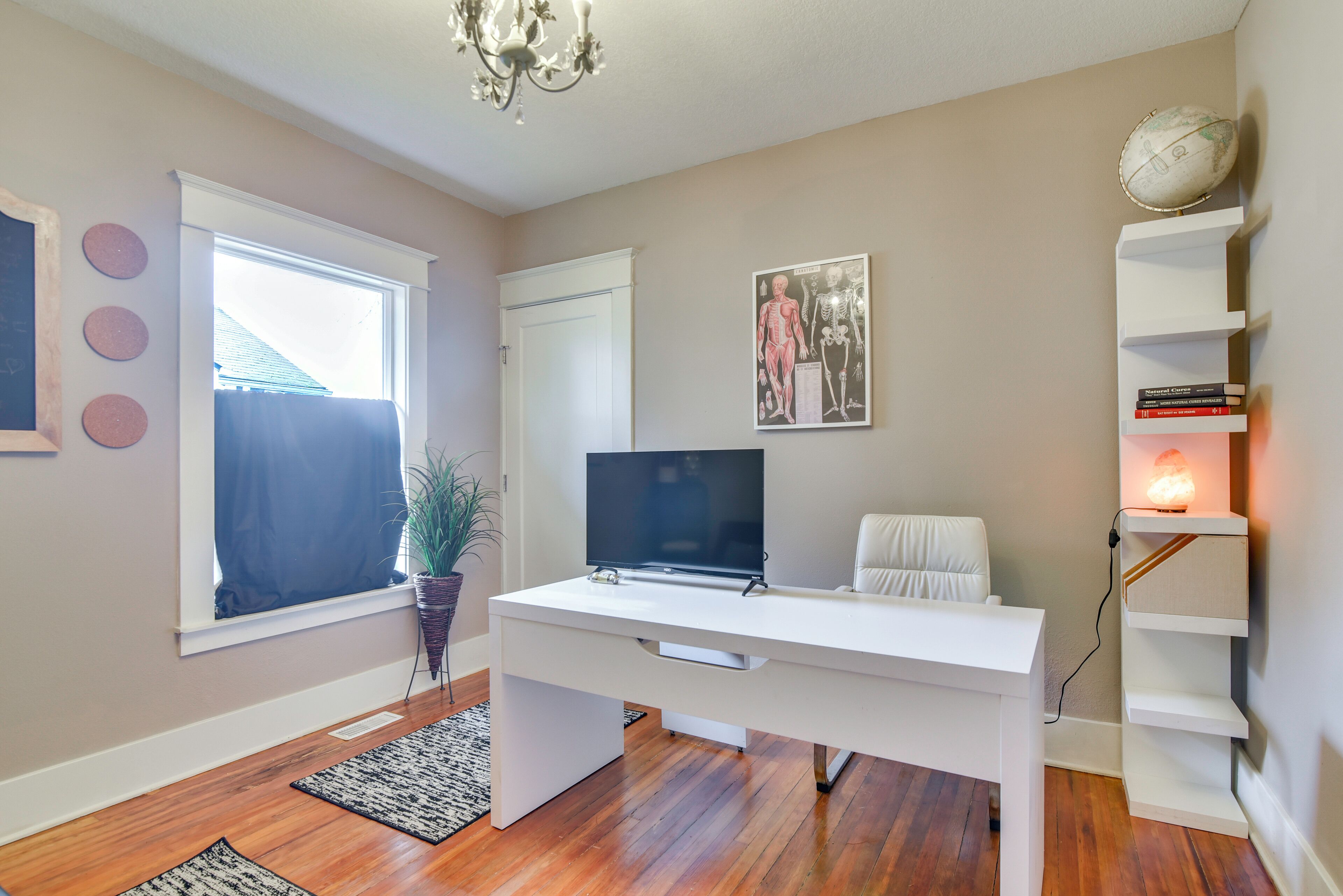 A modern room with a white desk, TV, and bookshelf.