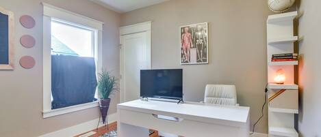 A modern room with a white desk, TV, and bookshelf.