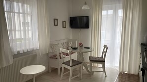 Una habitación con cama, una mesa, sillas, televisor y ventana con cortinas.