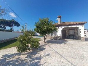 Ein Haus mit einer Stein-Fassade, einem Ziegeldach und einer Terrasse mit Tisch und Stühlen.