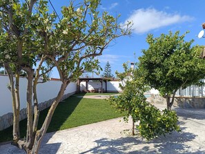 Eine Terrasse mit Rasenfläche, einer Pergola und einer Steinmauer.