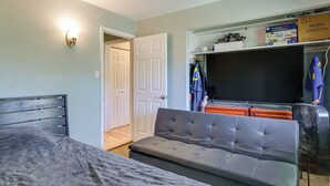 Ein Schlafzimmer mit Bett, einer Couch, einem Fernseher und einem Kleiderschrank.