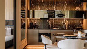 Une cuisine moderne avec un dosseret en marbre, des appareils électroménagers intégrés et un coin repas avec des chaises blanches.