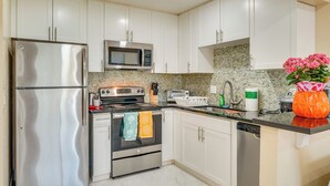 A modern kitchen with white cabinets, stainless steel appliances, and a tiled backsplash. - Walkable Pleasanton Condo Near Downtown w/ Balcony (Pleasanton)