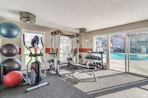 Une salle de sport équipée de matériel d’exercice, une piscine et une vue sur l’extérieur.