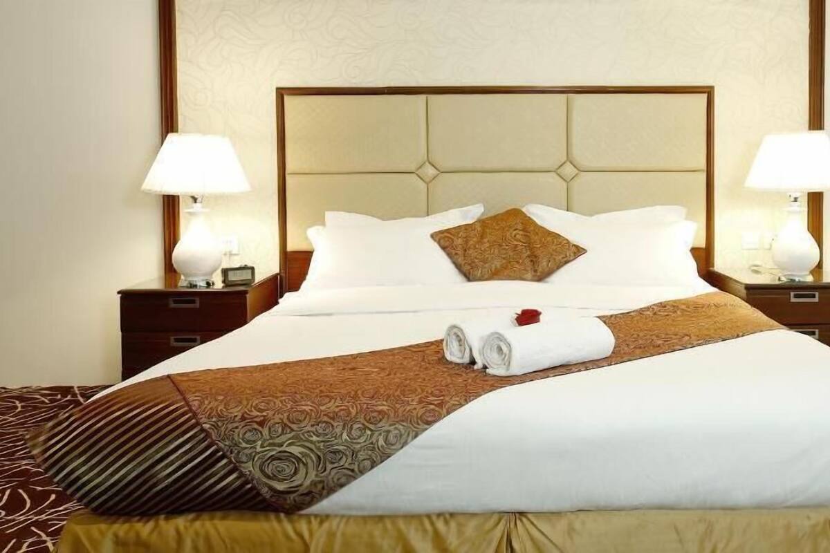 A hotel room with a large bed, two bedside tables with lamps, and a headboard.