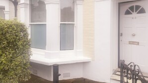 Ein weißes Reihenhaus mit Erkerfenstern, einer Haustür und einer kleinen Veranda.