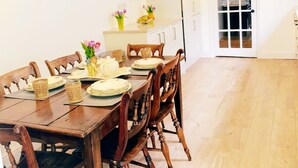 Ein Essbereich mit einem Holztisch, gedeckt für vier Personen, weißen Schränken, einer Mikrowelle und einer Tür zu einem Balkon.
