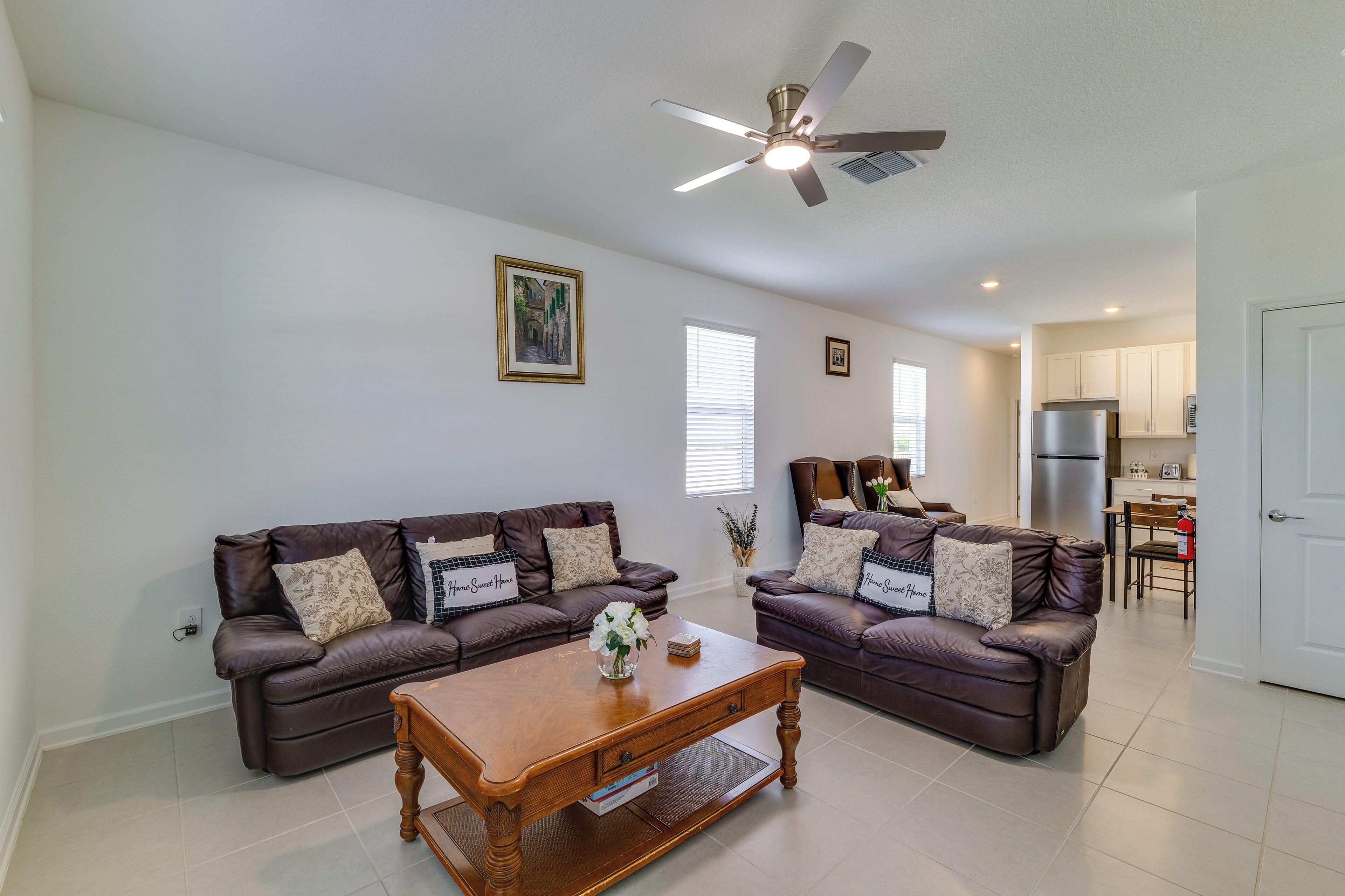 A living room with two brown leather sofas, a wooden coffee table, and a ceiling fan.