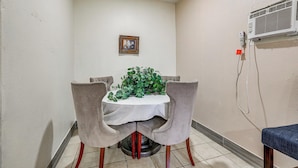 Un comedor con una mesa, sillas, una planta en maceta, un cuadro enmarco y un equipo de aire acondicionado.