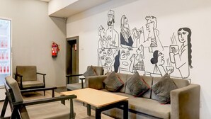 Ett modernt loungeområde med en soffa, stolar, ett bord och en väggmålning.
