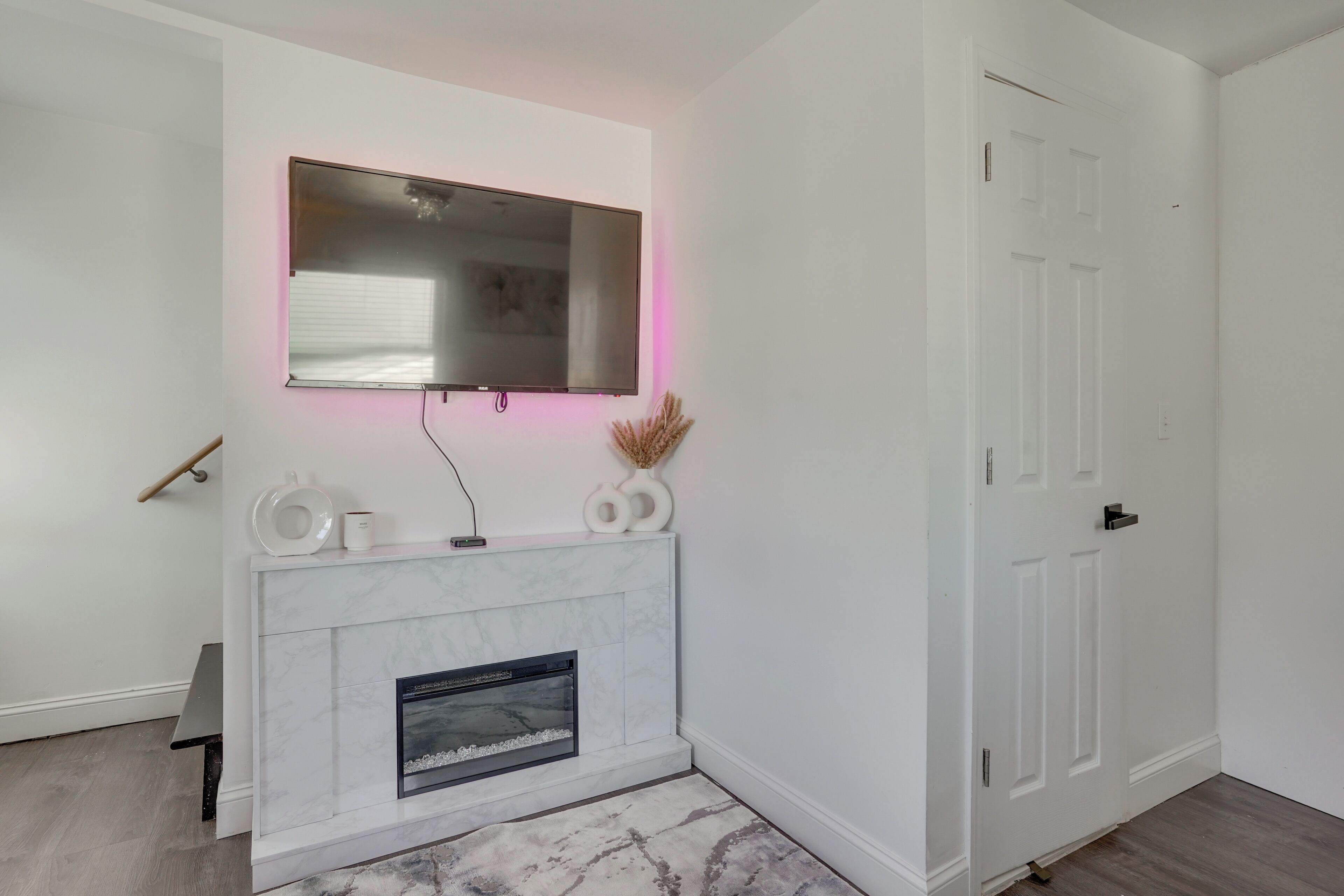 A modern interior with a white fireplace, a mounted TV, and a door.