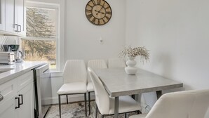 A modern kitchen with white cabinets, a built-in dishwasher, and a window with a view of trees. - Easy Access to Nyc! Sleek Suburban Apartment (Mamaroneck)