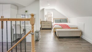 A bedroom with a bed, bedside table, lamp, and a view of the outside. - Easy Access to Nyc! Sleek Suburban Apartment (Mamaroneck)