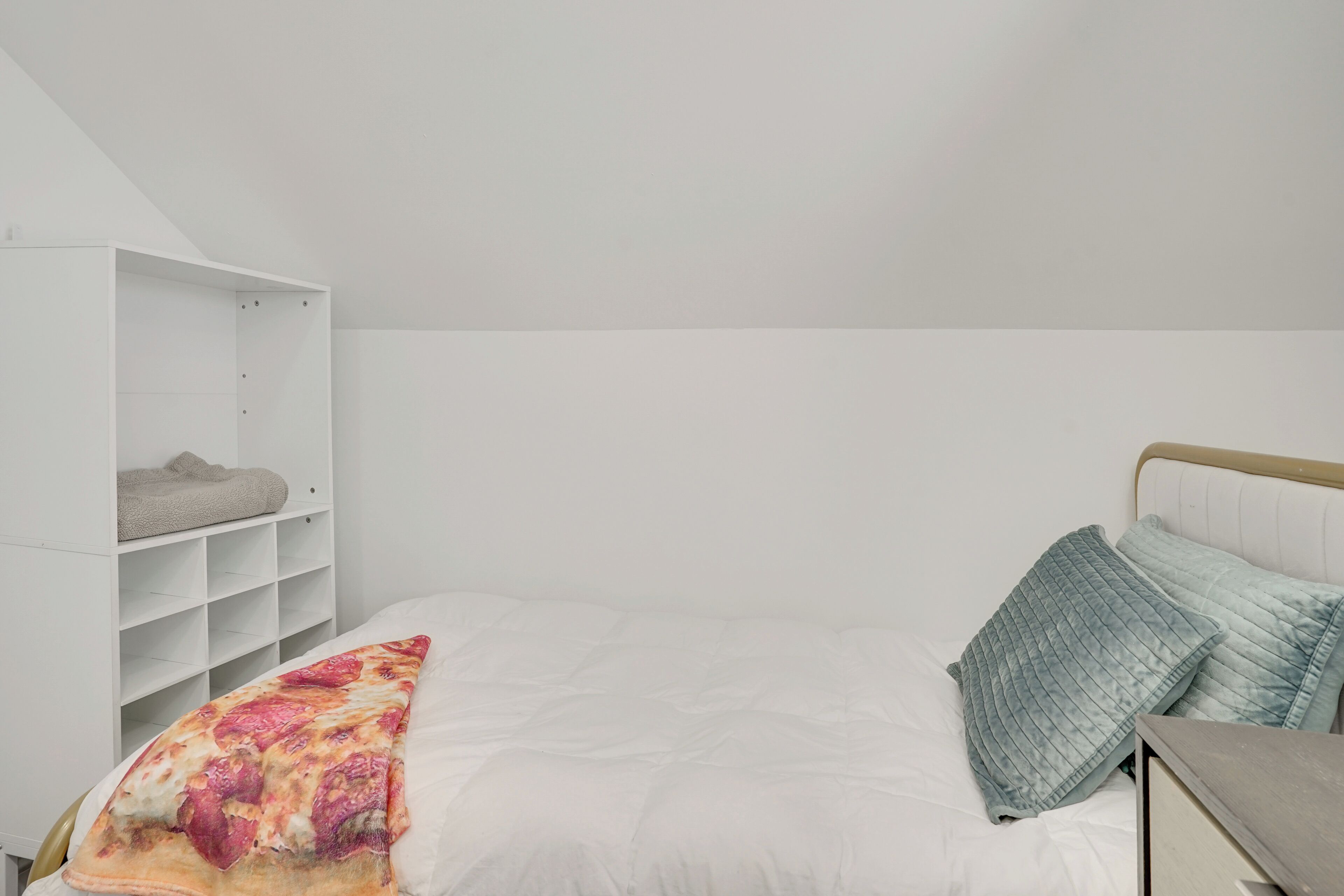 Quarto com cama, guarda-roupa branco e mesa de cabeceira.