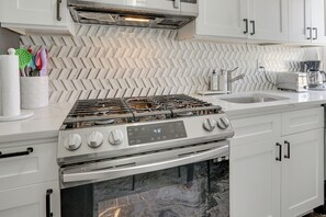 Een moderne keuken met een backsplash van visgraat tegels, roestvrijstalen apparatuur en witte kasten.