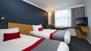 A hotel room with two beds, a TV, a desk, and a window with curtains. - Holiday Inn Express Peterborough (Peterborough)