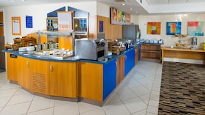 Uma área de buffet com balcão azul, eletrodomésticos de aço inoxidável e armários de madeira.
