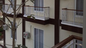 Un immeuble à plusieurs étages doté de balcons, de climatiseurs et d’un téléphone.
