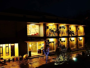 A two-story building with balconies, a visible window, and a well-lit entrance.