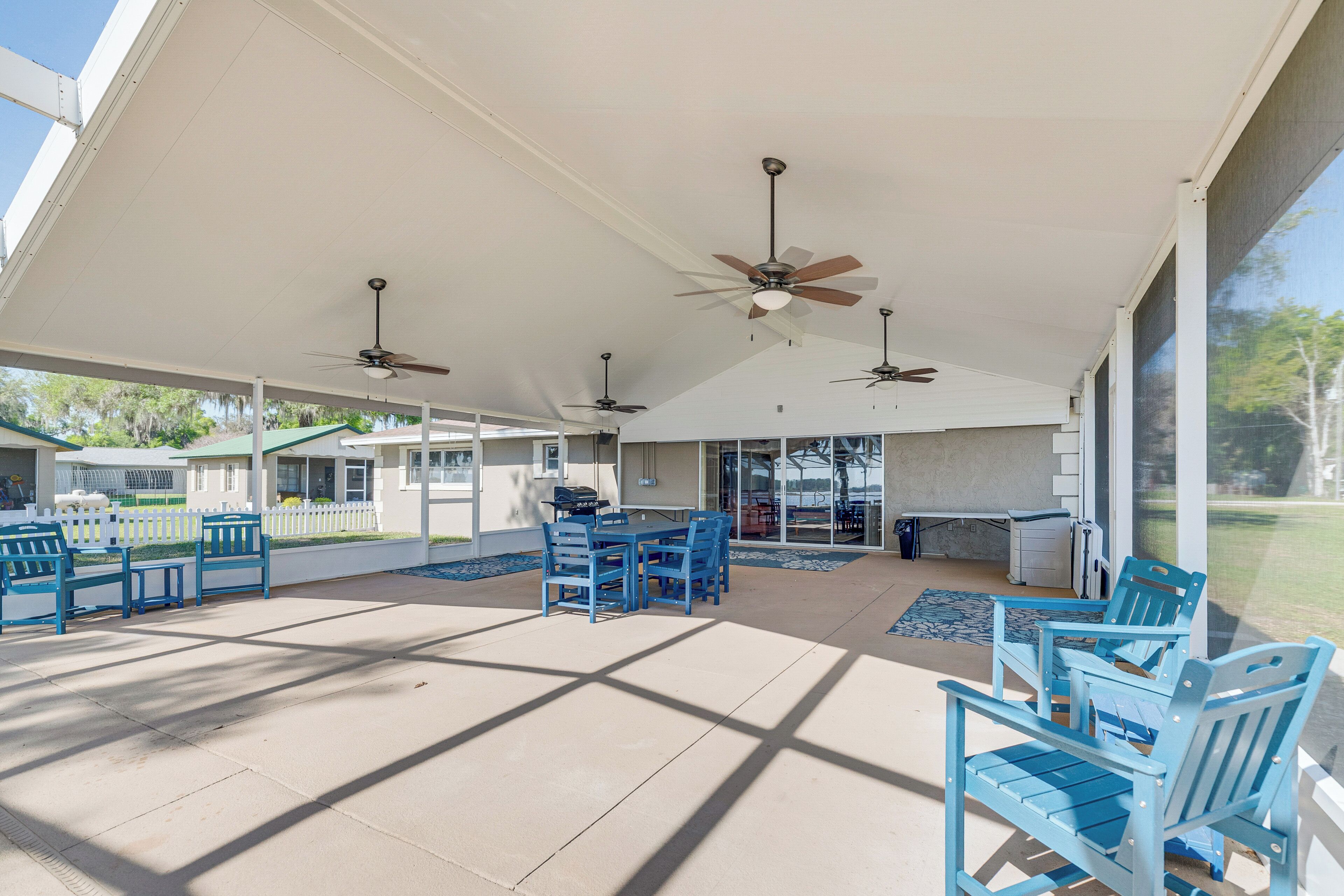 A covered outdoor area with ceiling fans, blue chairs, and a table.