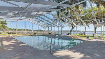 A covered swimming pool with a view of the lake and trees.