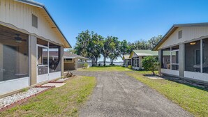 A row of single-story buildings with large windows, a gravel driveway, and a small tree in the center. - Paddle, Fish & Swim! Hernando Lake Cabin (Hernando)