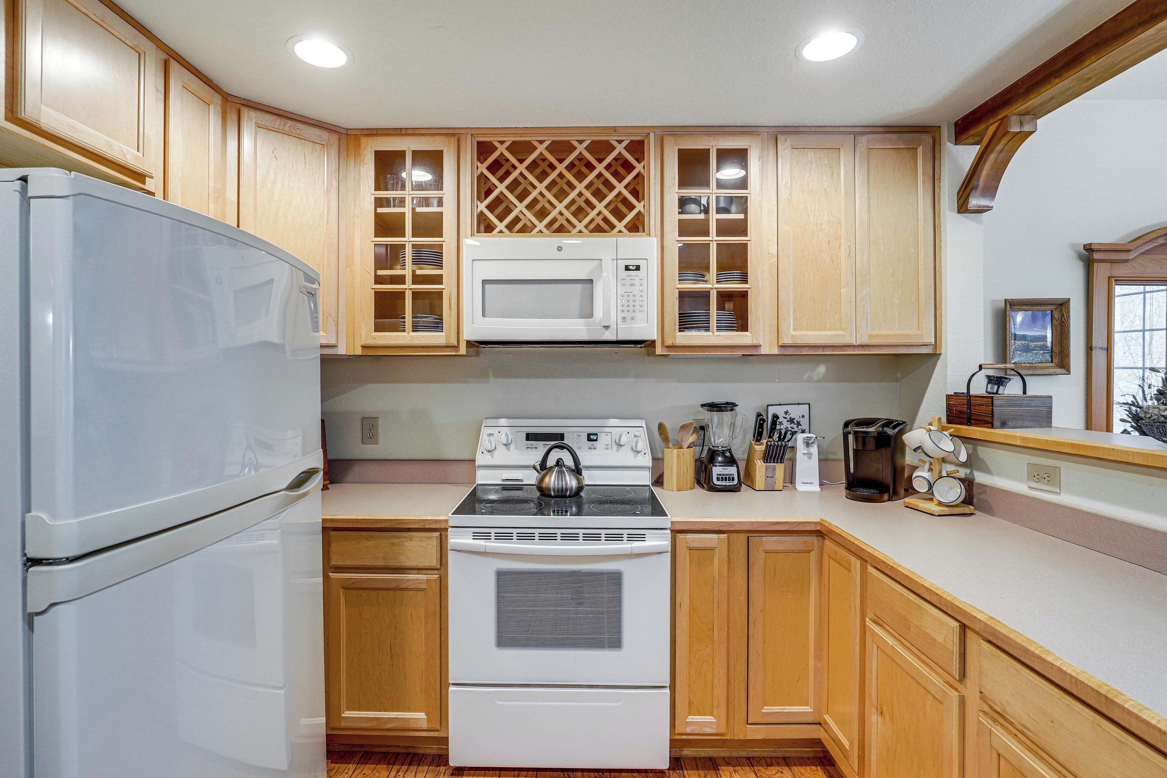 Una cocina con armarios de madera, un refrigerador blanco, un microondas, una estufa y una cafetera.