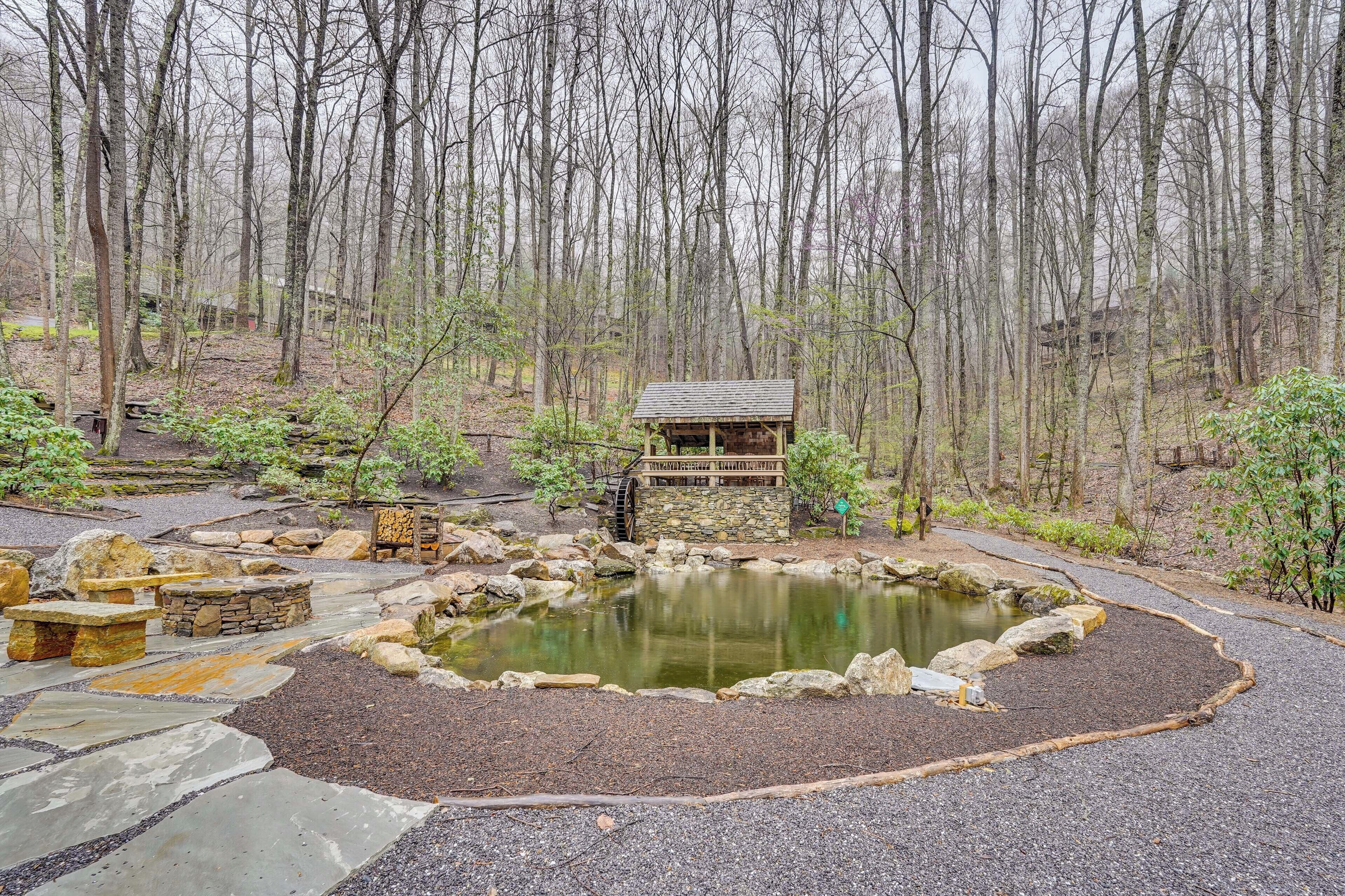 A rustic cabin surrounded by a pond and stone pathways.